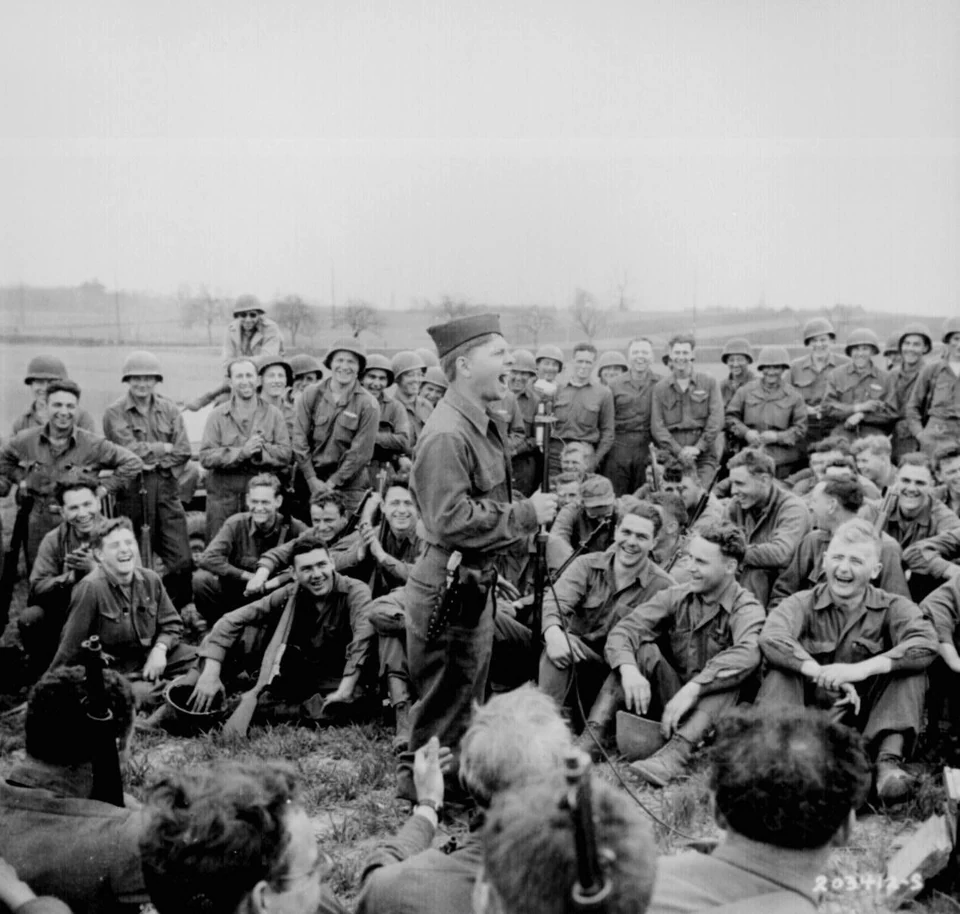 Mickey Rooney standing among a large group of US soldiers outdoors